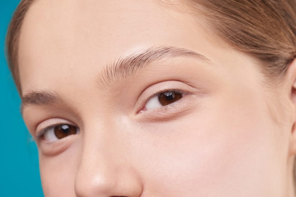 woman looking at the camera. she has clear skin and brown eyes.