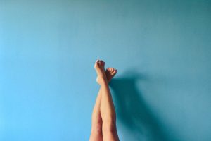 a woman's bare legs are up against a blue wall.