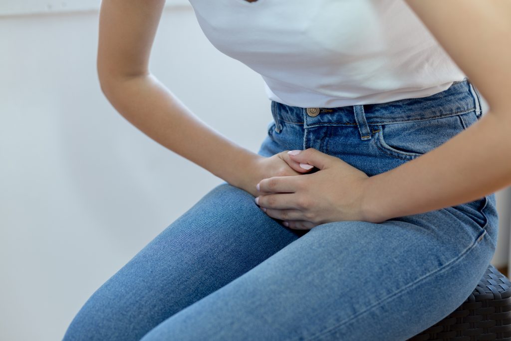 woman bending over, clutching her lower abdomen.