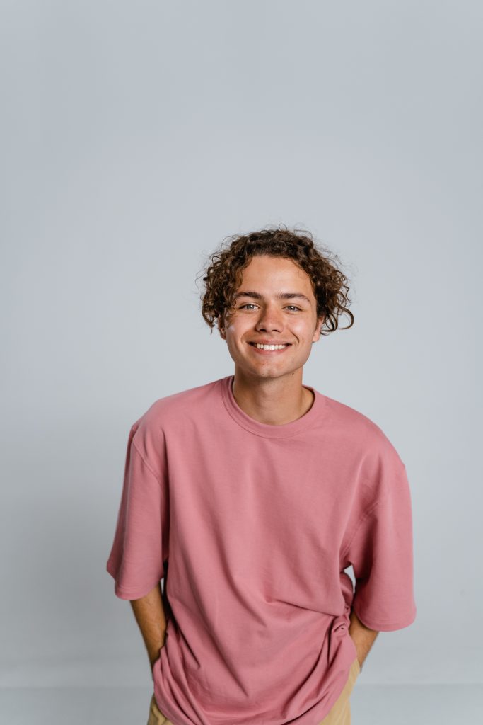 a teenage boy smiles at the camera with a blemish free face.