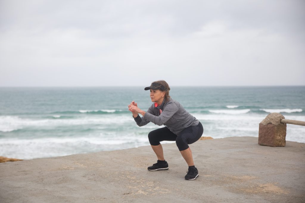 a mature aged woman does exercise along the coast line