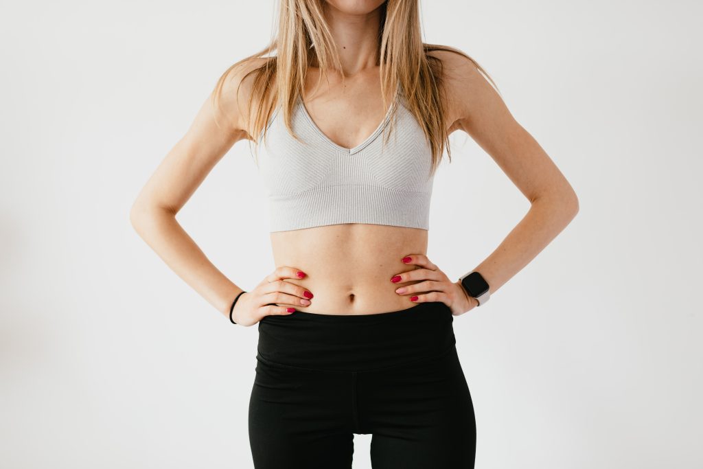 a woman has a slim figure and wears active wear. she has her hands on her hips.